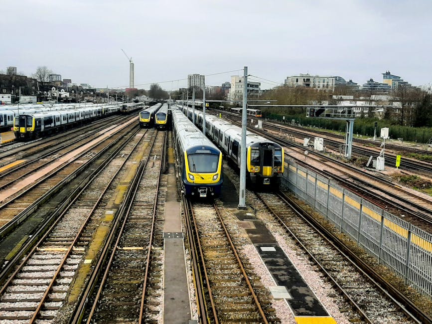 A view of multiple modern trains parked on parallel railway tracks near Palmers Green station in N13. The trains are primarily white with yellow front panels, and some are positioned on the left side 
